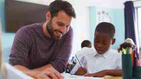 Teacher helps student with their work in a classroom.