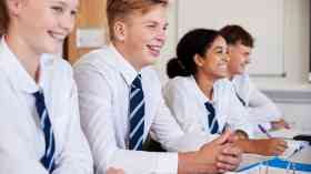 Secondary students sat at a desk in a row.