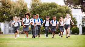 Primary school children run across a field.